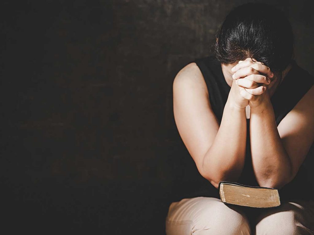 Woman head down in prayer | All Are Guilty from Share The Gift's weekly newsletter The Message